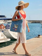 Front view of a dusty blue canvas tote bag featuring a central embroidery of a French Bulldog wearing black sunglasses and a red, white, and blue American flag bandana