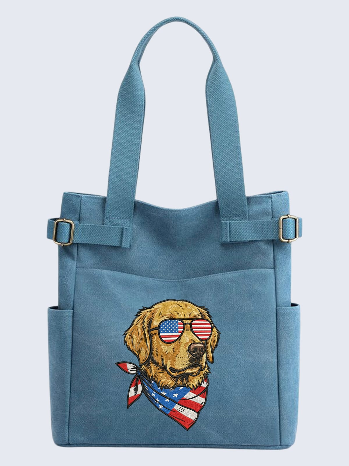 blue-canvas-tote-bag-golden-retriever-american-flag-glasses A light blue canvas tote bag featuring an embroidered Golden Retriever wearing sunglasses with an American flag lens pattern and a matching patriotic bandana