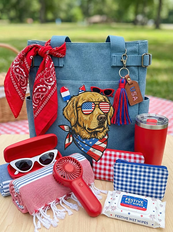 Medium-sized patriotic tote bag showcasing its spacious interior and exterior pockets, packed with Fourth of July picnic essentials to demonstrate its versatile 'day out' functionality.